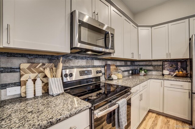 1341 Solitaire St, Colorado Springs, CO 80905 - kitchen featuring light stone countertops, light wood-style flooring, decorative backsplash, and stainless steel appliances