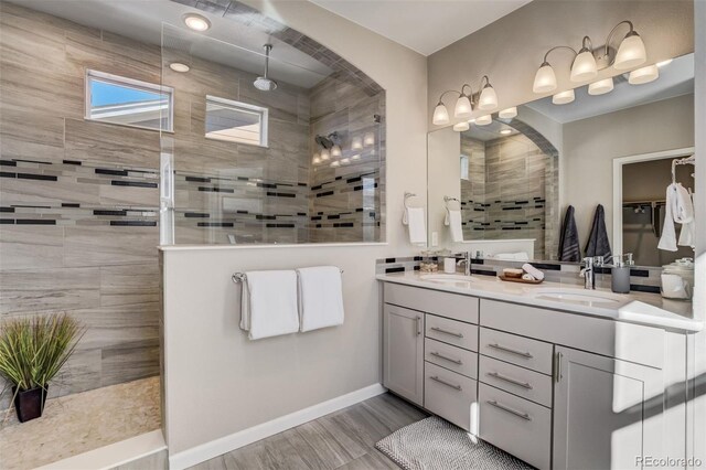 1341 Solitaire St, Colorado Springs, CO 80905 - bathroom featuring baseboards, double vanity, a sink, and a walk in shower