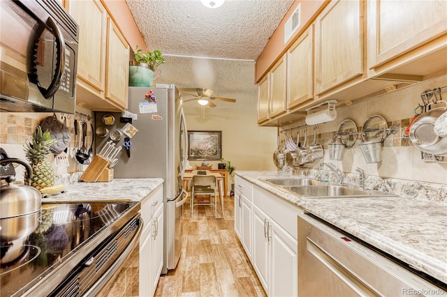 kitchen with sink, ceiling fan, light wood-type flooring, a textured ceiling, and stainless steel appliances