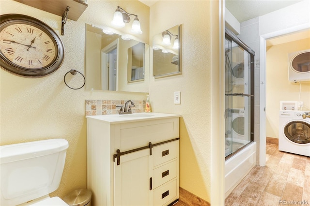 full bathroom featuring decorative backsplash, vanity, hardwood / wood-style flooring, enclosed tub / shower combo, and washer / dryer