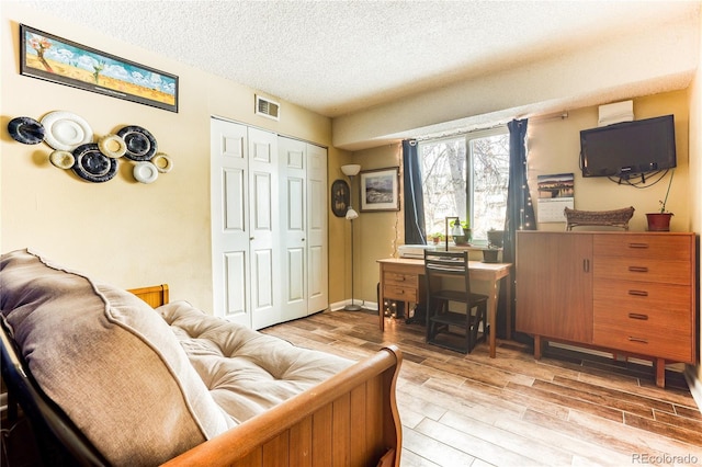 interior space with a textured ceiling and light hardwood / wood-style flooring