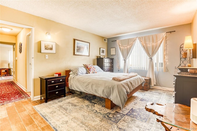 bedroom featuring light hardwood / wood-style floors and a textured ceiling