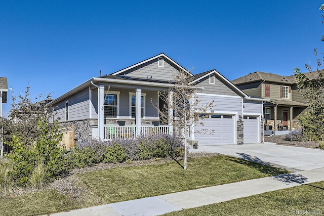 view of front of property featuring covered porch, a garage, and a front yard