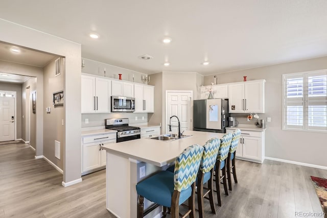 kitchen featuring white cabinetry, stainless steel appliances, sink, and a center island with sink