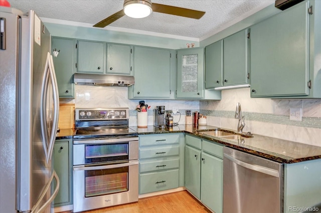 kitchen with under cabinet range hood, stainless steel appliances, a sink, a textured ceiling, and ceiling fan