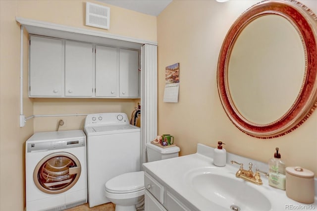 bathroom featuring visible vents, washing machine and clothes dryer, vanity, and toilet