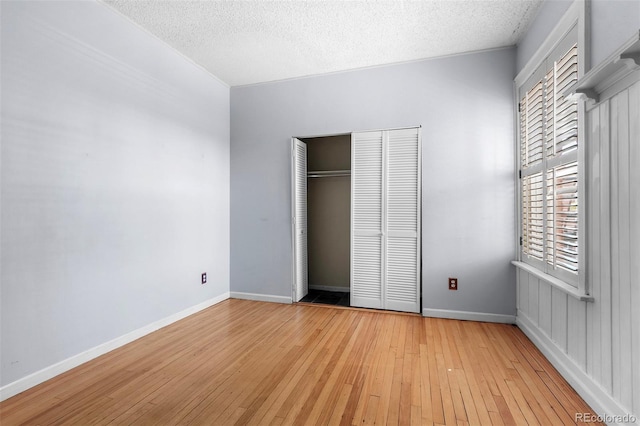 unfurnished bedroom with multiple windows, a textured ceiling, and light hardwood / wood-style flooring