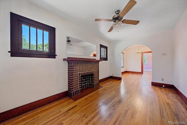 unfurnished living room featuring hardwood / wood-style flooring, ceiling fan, and a brick fireplace