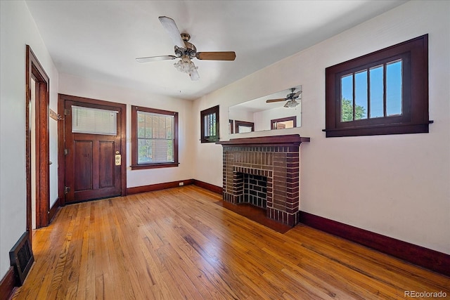 unfurnished living room with ceiling fan, light hardwood / wood-style floors, and a brick fireplace