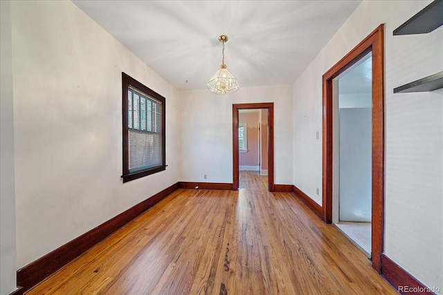 spare room with light wood-type flooring and a chandelier