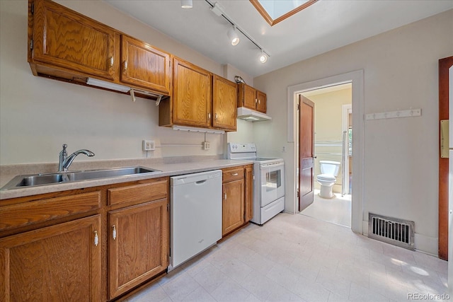 kitchen with white appliances, sink, and a skylight