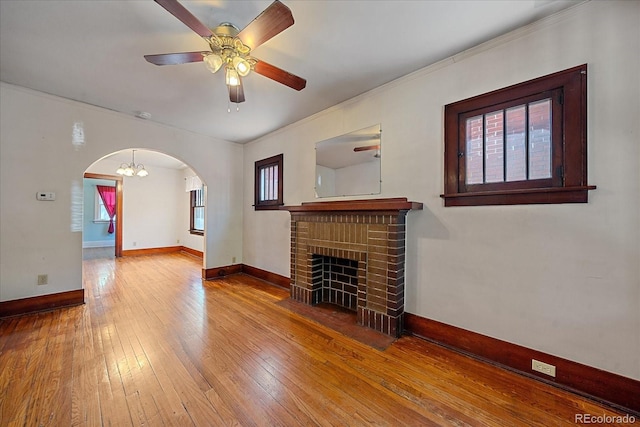 unfurnished living room featuring hardwood / wood-style flooring, ceiling fan with notable chandelier, and a brick fireplace