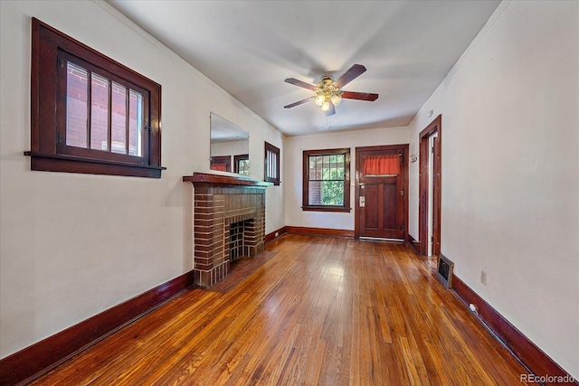 unfurnished living room featuring dark hardwood / wood-style floors, a brick fireplace, and ceiling fan