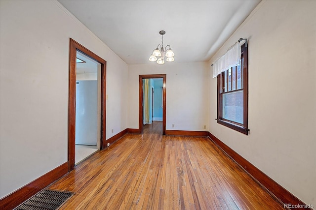 spare room with light hardwood / wood-style flooring and a notable chandelier