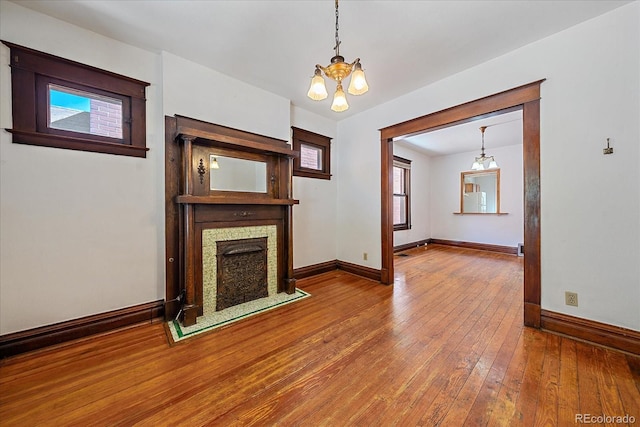 unfurnished living room with wood-type flooring and an inviting chandelier