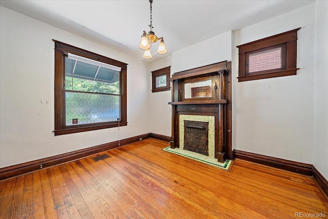 unfurnished living room featuring wood-type flooring and a notable chandelier