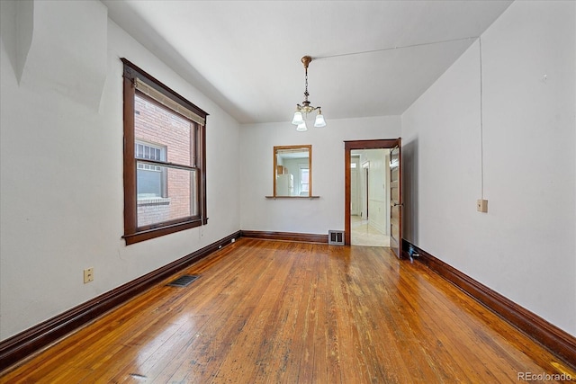 spare room featuring a chandelier and wood-type flooring