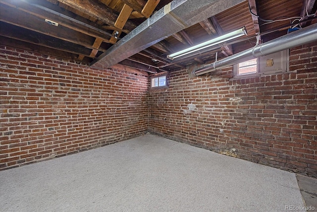 basement featuring carpet flooring and brick wall