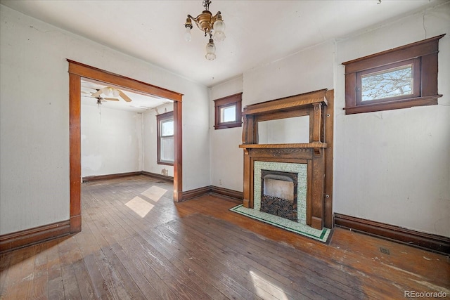 unfurnished living room featuring hardwood / wood-style floors and ceiling fan with notable chandelier