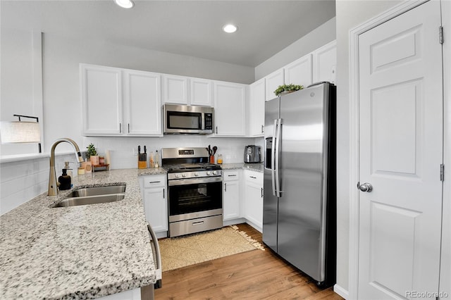 6459 N Dunkirk St, Denver, CO 80249 - kitchen featuring appliances with stainless steel finishes, a sink, light wood-style floors, white cabinetry, and recessed lighting