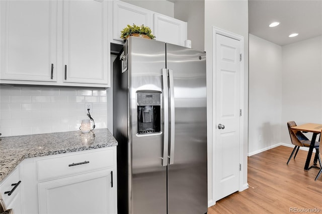6459 N Dunkirk St, Denver, CO 80249 - kitchen featuring stainless steel refrigerator with ice dispenser, light wood-type flooring, decorative backsplash, white cabinets, and baseboards