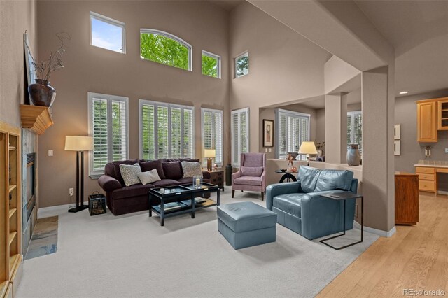 10524 Serengeti Dr, Lone Tree, CO 80124 - living area featuring a tiled fireplace, a towering ceiling, and baseboards