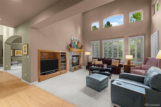 10524 Serengeti Dr, Lone Tree, CO 80124 - living area with a towering ceiling, arched walkways, a tile fireplace, wood finished floors, and healthy amount of natural light