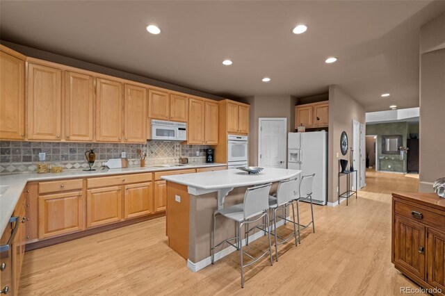10524 Serengeti Dr, Lone Tree, CO 80124 - kitchen featuring white appliances, a kitchen breakfast bar, tasteful backsplash, a kitchen island, and light wood finished floors
