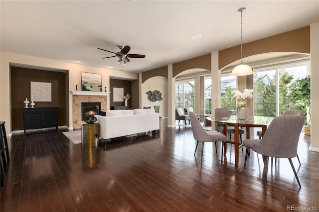 dining room with dark wood-type flooring, a glass covered fireplace, plenty of natural light, and baseboards