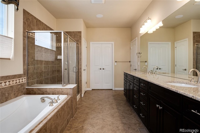 bathroom featuring double vanity, a stall shower, tile patterned floors, a sink, and a closet