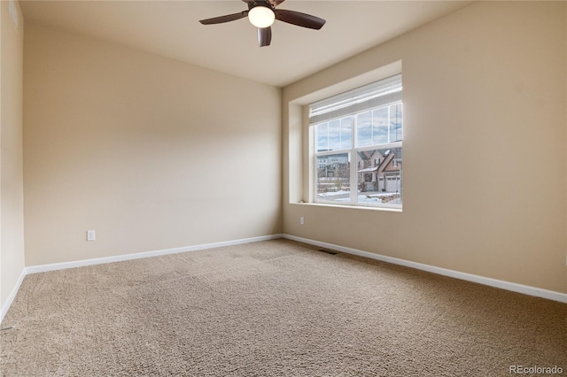 carpeted empty room featuring ceiling fan, visible vents, and baseboards