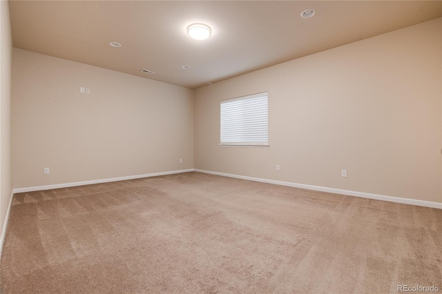 spare room with visible vents, baseboards, and light colored carpet