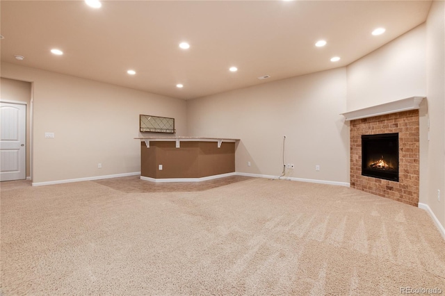 unfurnished living room with light carpet, a fireplace, baseboards, and recessed lighting