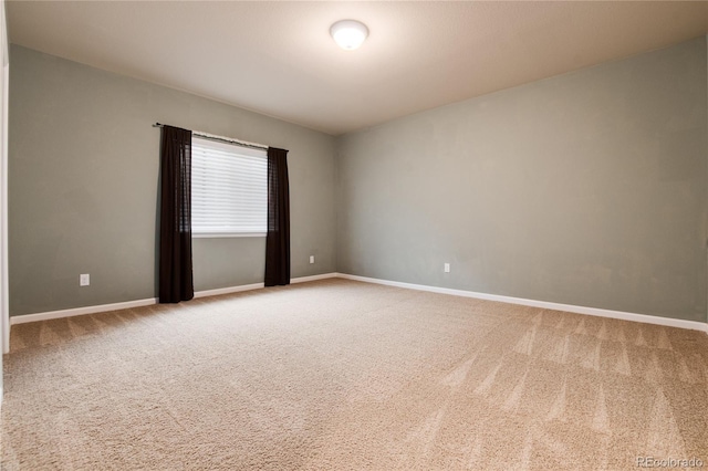 carpeted empty room featuring baseboards