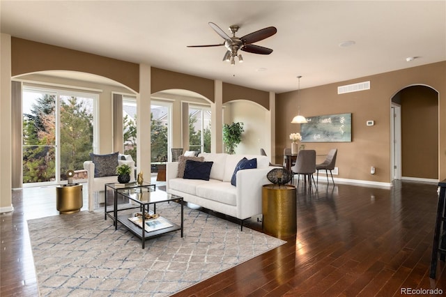 living room with a ceiling fan, wood finished floors, visible vents, and baseboards