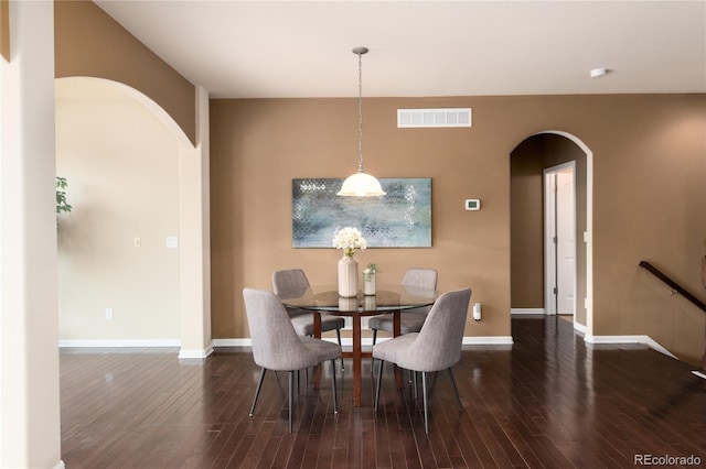 dining room featuring arched walkways, dark wood-type flooring, visible vents, and baseboards