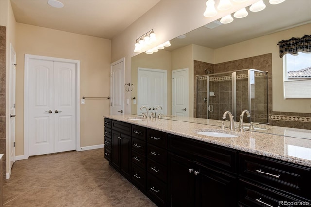 bathroom featuring double vanity, a stall shower, a sink, and tile patterned floors