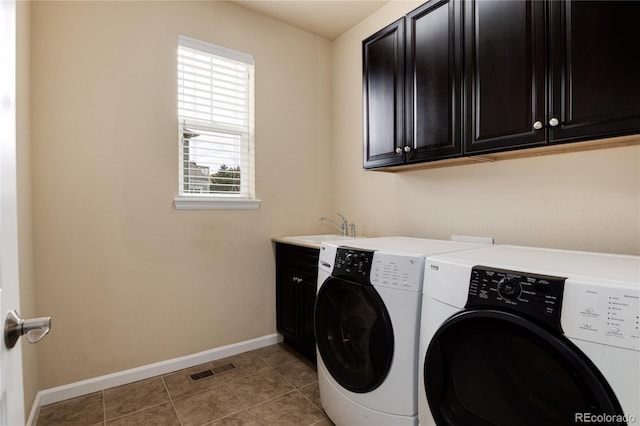 washroom with a sink, visible vents, baseboards, washer and dryer, and cabinet space