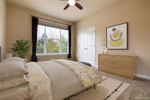 bedroom with baseboards, ceiling fan, a closet, and light carpet