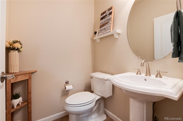 half bathroom with baseboards and toilet