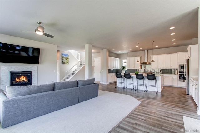 9571 Yucca Ct, Arvada, CO 80007 - living room with a ceiling fan, a glass covered fireplace, recessed lighting, wood finished floors, and stairs