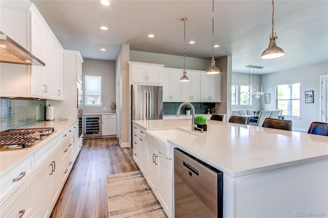 9571 Yucca Ct, Arvada, CO 80007 - kitchen with appliances with stainless steel finishes, a sink, wall chimney range hood, recessed lighting, and beverage cooler