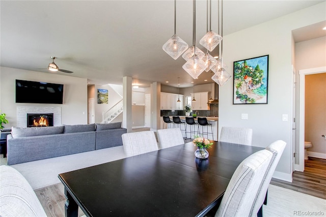 9571 Yucca Ct, Arvada, CO 80007 - dining area featuring stairway, a ceiling fan, light wood-style floors, and a glass covered fireplace