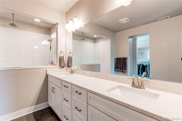 9571 Yucca Ct, Arvada, CO 80007 - bathroom with double vanity, tiled shower, baseboards, a spacious closet, and recessed lighting