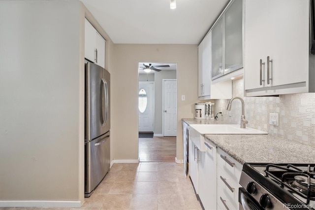 1817 S Perry Way, Denver, CO 80219 - kitchen featuring freestanding refrigerator, a ceiling fan, decorative backsplash, light tile patterned floors, and white cabinetry