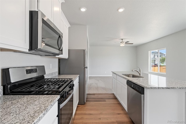 kitchen with light hardwood / wood-style flooring, white cabinetry, stainless steel appliances, sink, and ceiling fan