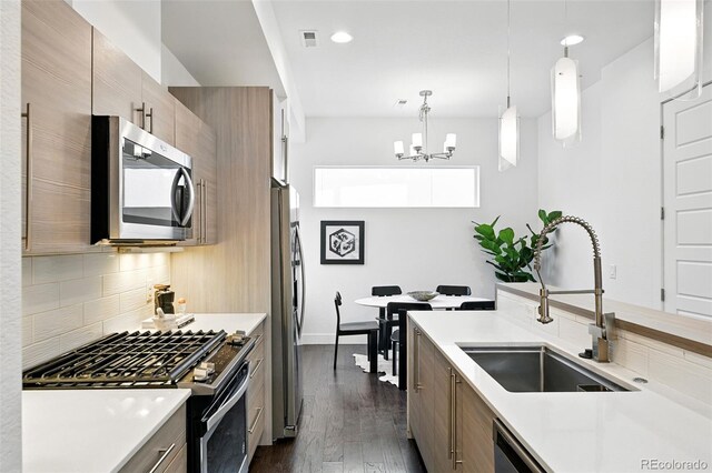 2830 W 32nd Ave, Denver, CO 80211 - kitchen with stainless steel appliances, tasteful backsplash, light countertops, dark wood-type flooring, and hanging light fixtures