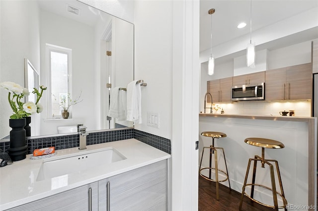 2830 W 32nd Ave, Denver, CO 80211 - bathroom with decorative backsplash, vanity, and wood finished floors