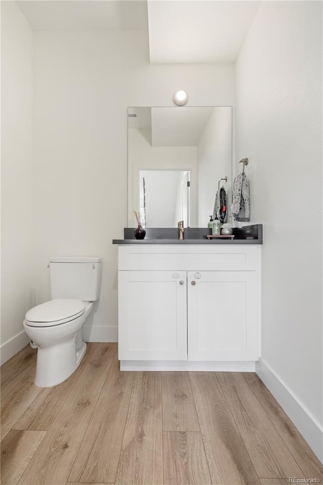 2012 W 46th Ave, Denver, CO 80211 - half bathroom featuring vanity, toilet, baseboards, and wood finished floors