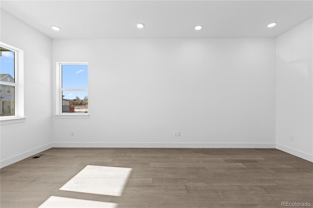 empty room featuring baseboards, wood finished floors, visible vents, and recessed lighting